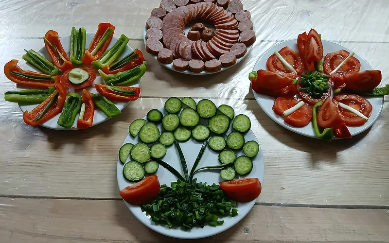 Cuatro platos de verdura y embutido sobre una mesa de madera